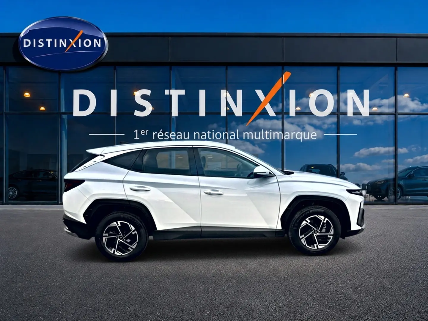 Vue de profil côté gauche du Hyundai Tucson blanc 2026 hybride, avec jantes alliage et lignes modernes distinctives.