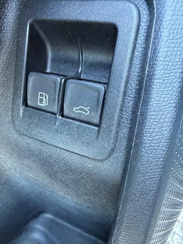 Gros plan sur les boutons d’ouverture de trappe à carburant et coffre dans l’habitacle noir du CUPRA Formentor 2024.