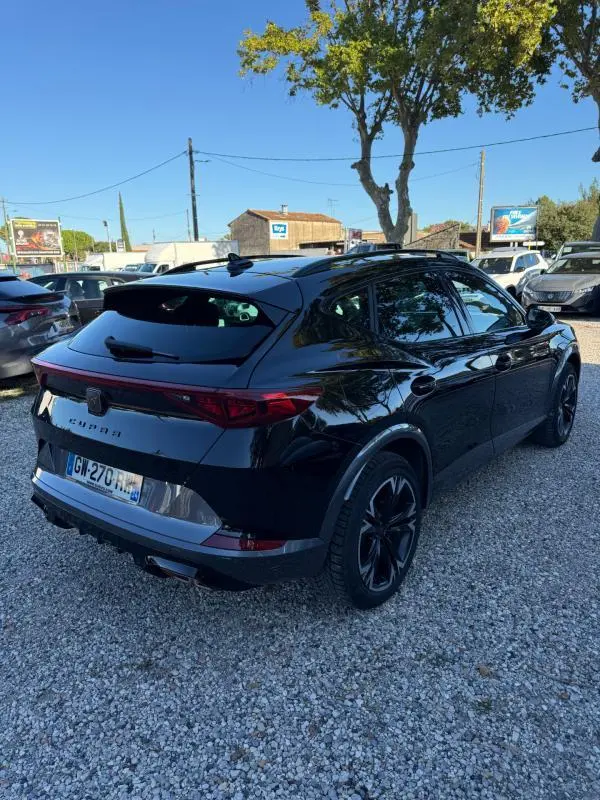 Vue 3/4 arrière droite d'une CUPRA Formentor noir brillant 2024, avec feux arrière étirés et jantes noires distinctives.