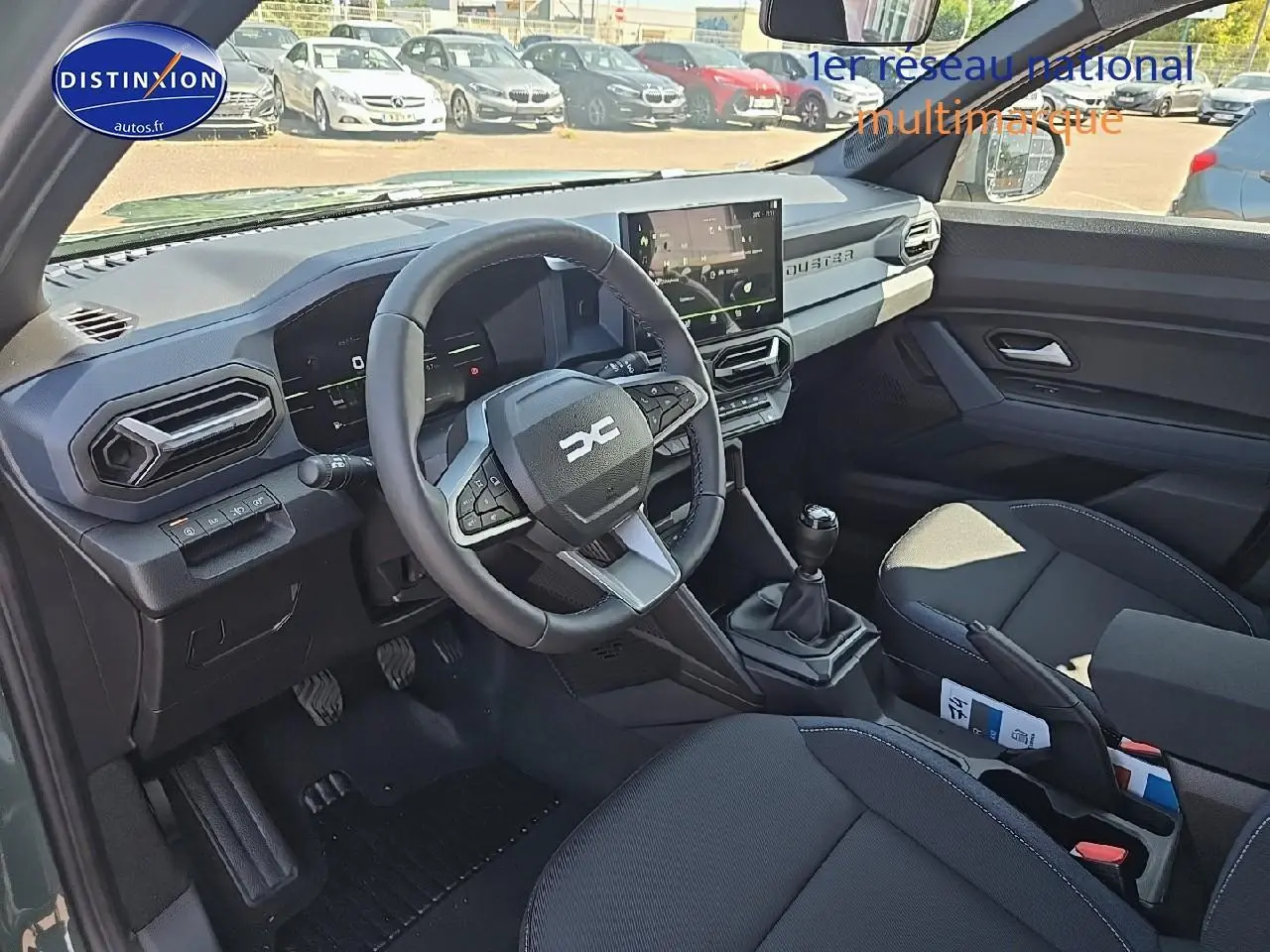 Intérieur avant du Dacia Duster 2025 vert kaki, volant multifonction, boîte manuelle et écran tactile central visible.