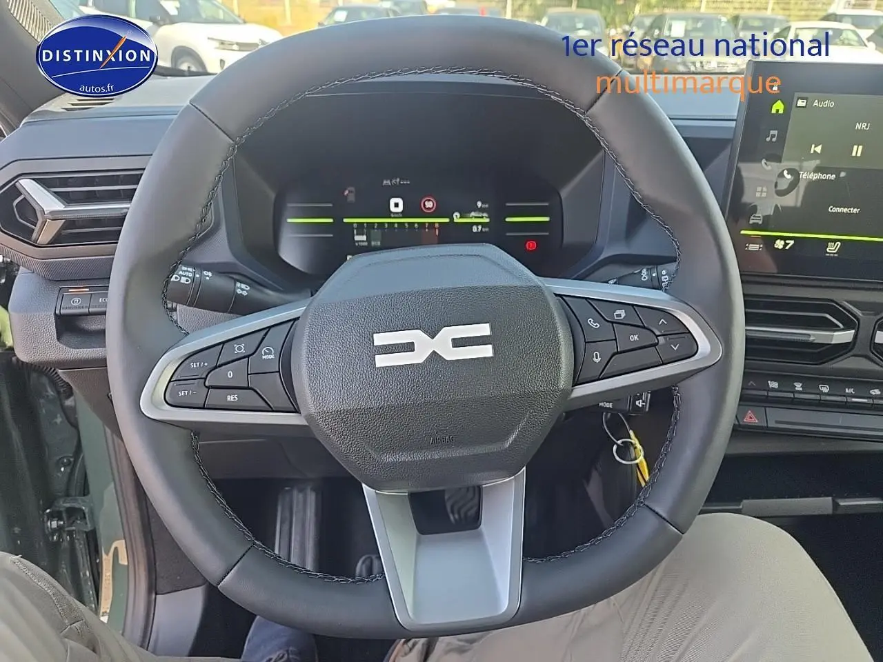 Vue intérieure centrée sur le volant multifonction du Dacia Duster vert kaki 2025 avec tableau de bord digital et écran tactile.