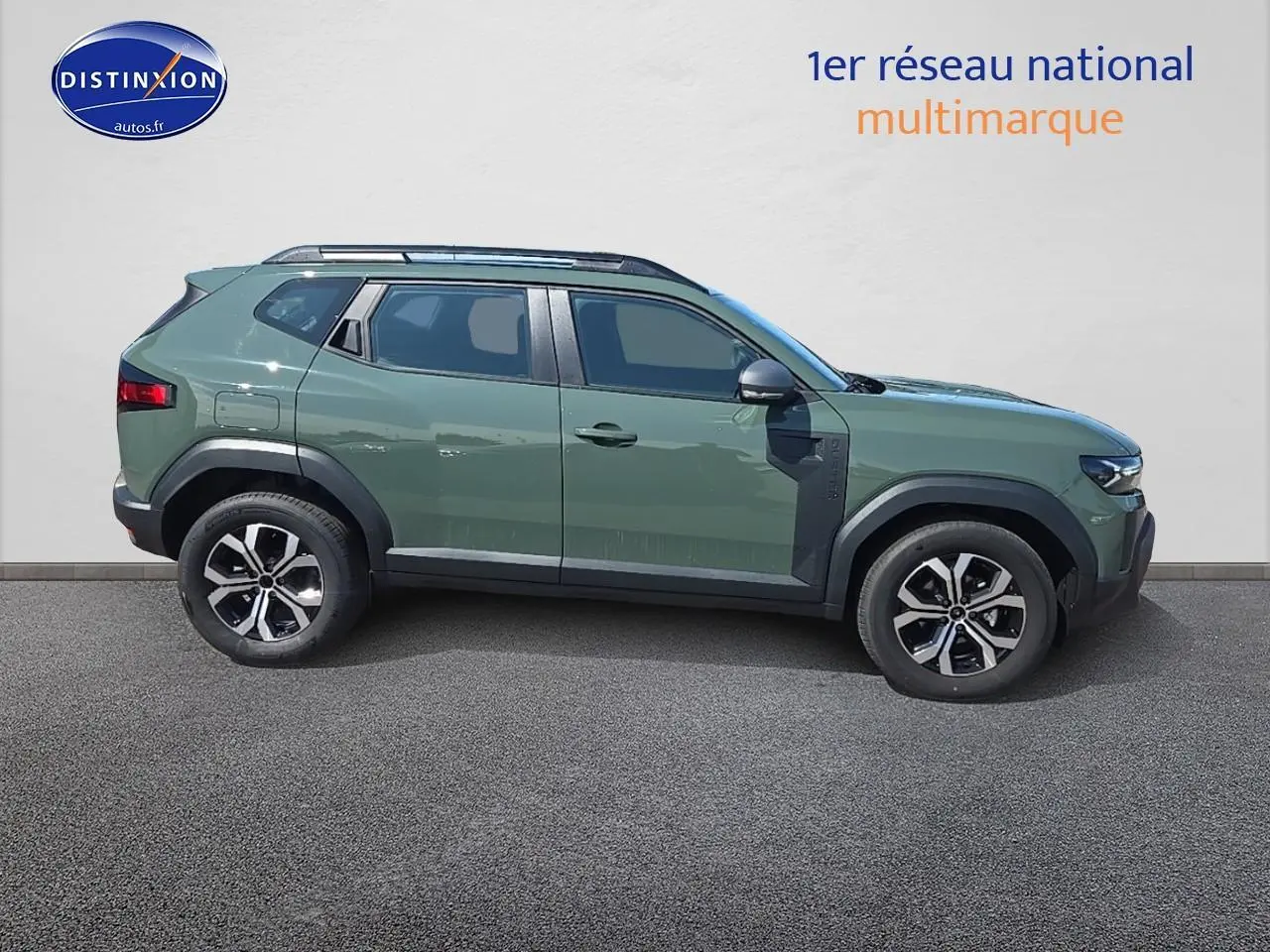Profil droit du Dacia Duster 2025 vert kaki avec barres de toit et jantes alu noires et argentées.