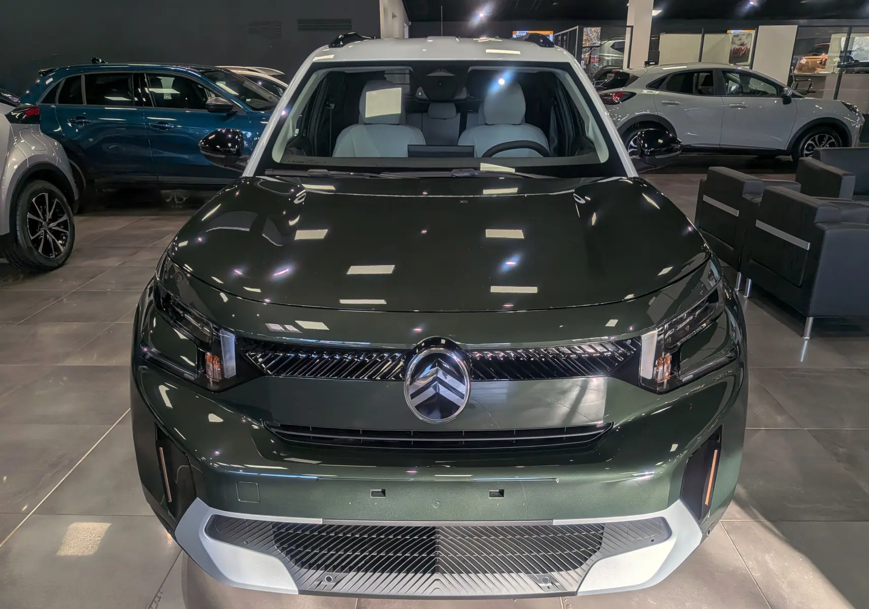 Citroën C3 Aircross hybride 2025 vue de face, vert Montana avec toit blanc en showroom moderne.