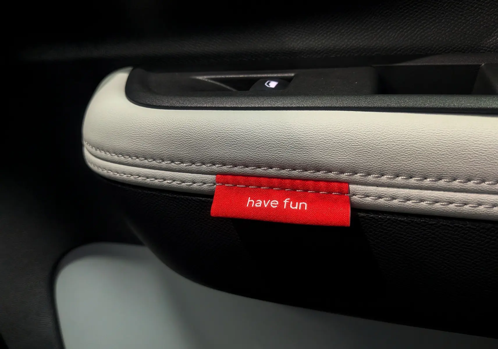 Gros plan sur la poignée de porte intérieure en cuir blanc et noir du Citroën C3 Aircross hybride avec étiquette rouge "have fun"