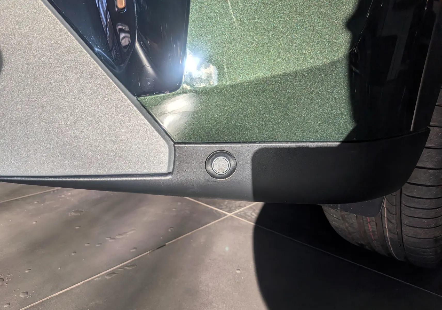 Gros plan sur le bas du pare-chocs avant vert Montana du Citroën C3 Aircross hybride avec capteur de stationnement visible.