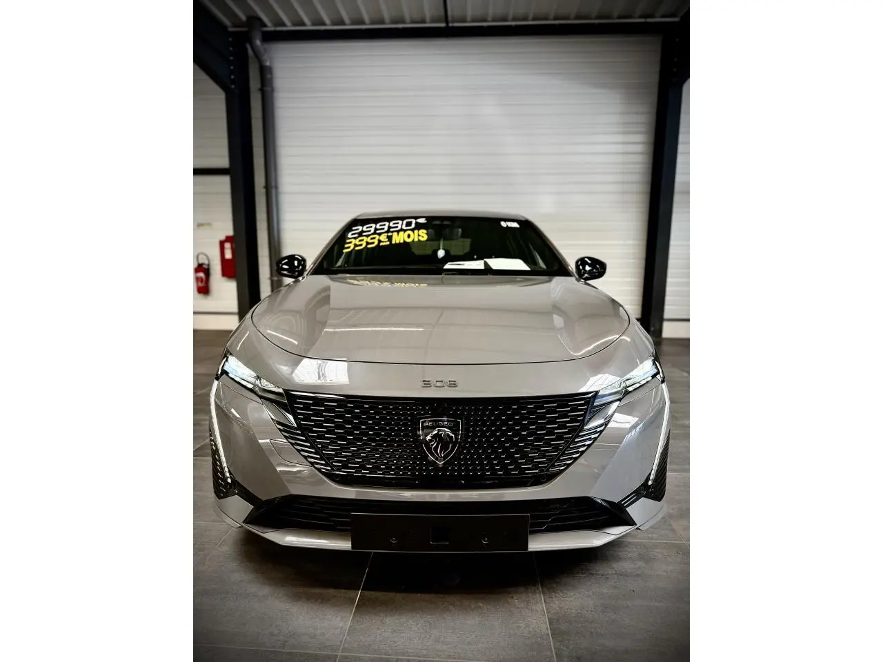 Vue avant de la Peugeot 308 GT gris selenium avec calandre noire brillante et feux LED griffés.