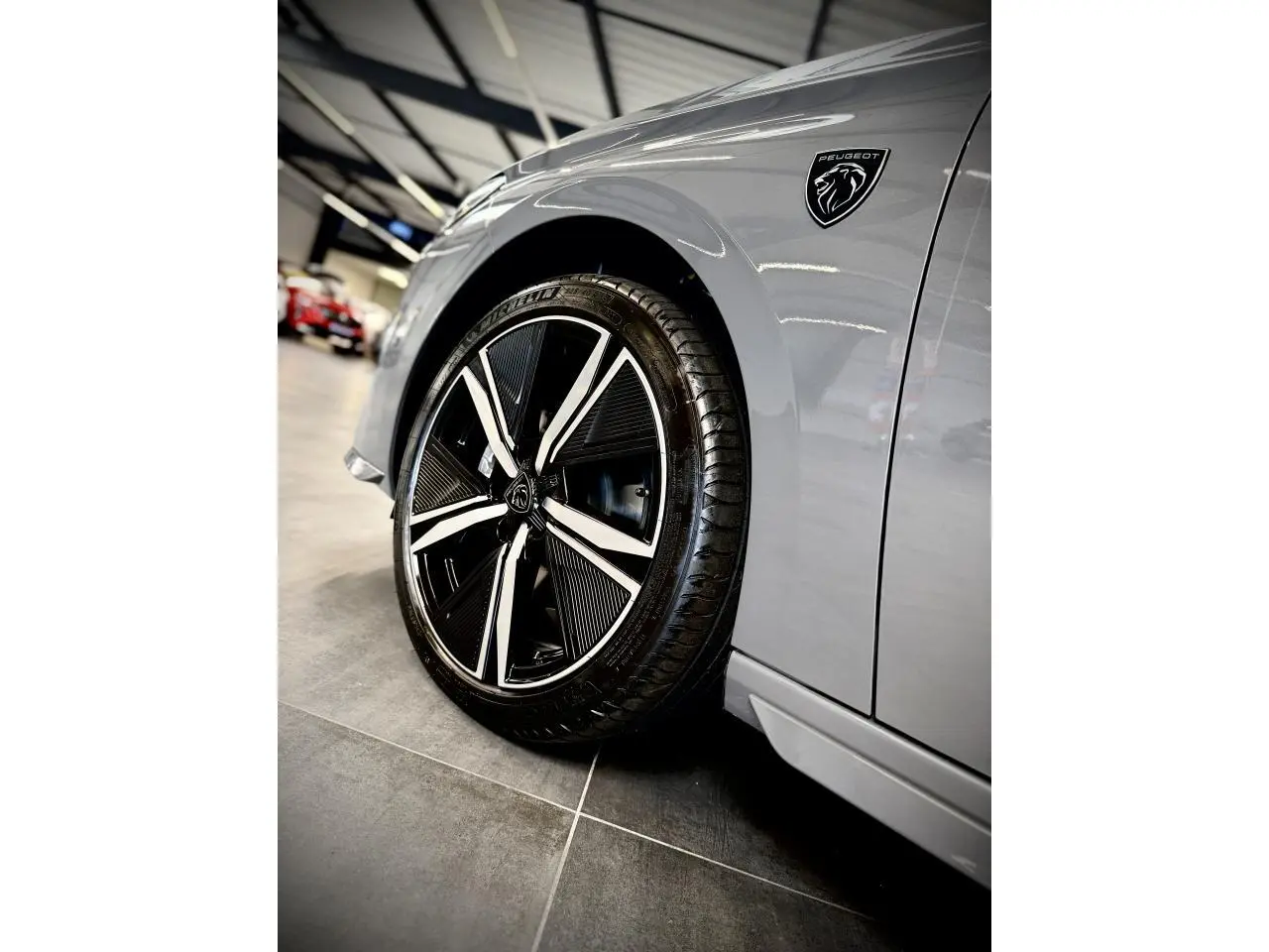 Gros plan sur la roue avant gauche et l’aile gris sélénium d’une Peugeot 308 avec logo noir brillant Lion.