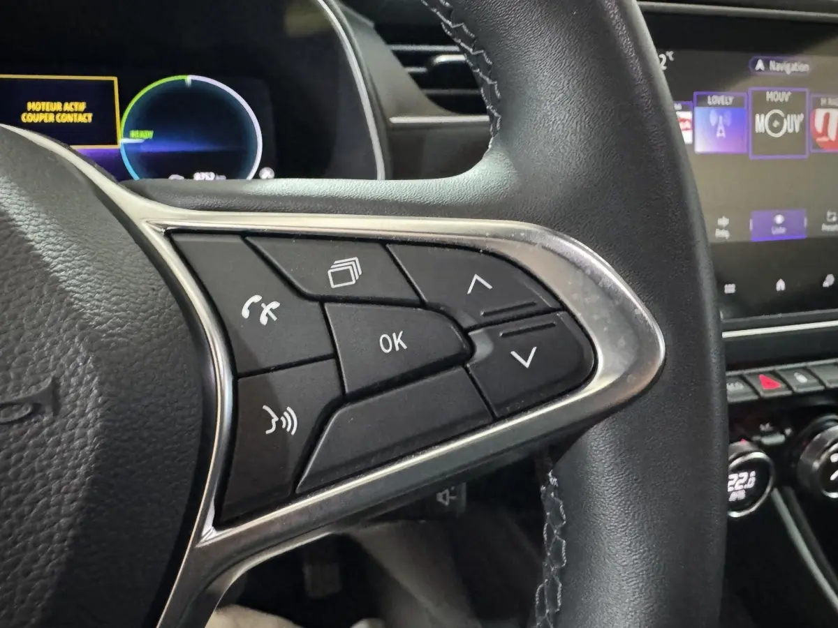 Gros plan sur les commandes au volant à droite en cuir noir de la Renault ZOE Business Rev R110 2020, avec écran tactile en arrière-plan.