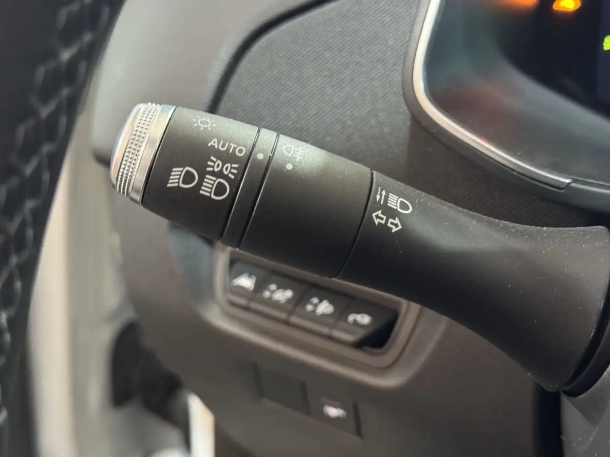 Gros plan sur la commande des phares et clignotants dans l'habitacle d'une Renault ZOE blanche de 2020.