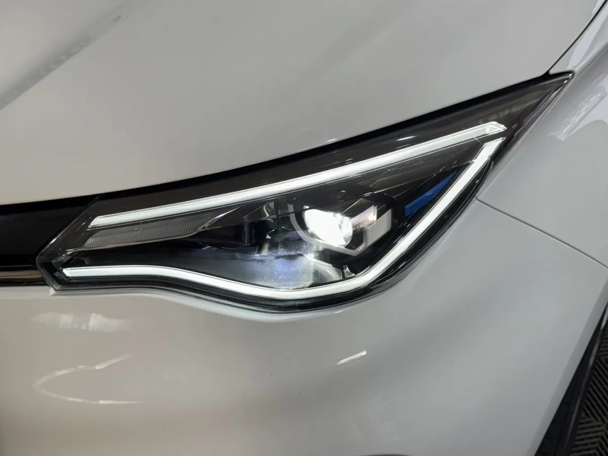 Gros plan sur le phare avant droit allumé d'une Renault ZOE Business Rev R110 blanche de 2020.