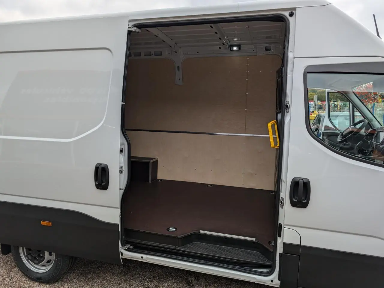 Vue latérale droite d’un Iveco Daily blanc 2025 avec porte coulissante ouverte montrant l’espace de chargement vide et habillé.