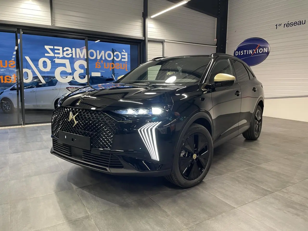 DS7 Crossback noir métallisé en 3/4 avant droit, avec calandre DS Wings et rétroviseurs dorés satinés visibles en showroom.
