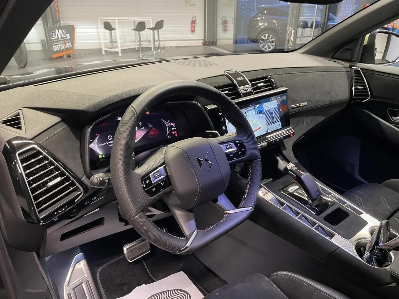 Vue intérieure côté conducteur du DS7 Crossback 2026, volant cuir perforé, tableau de bord numérique et console centrale en Alcantara noir.