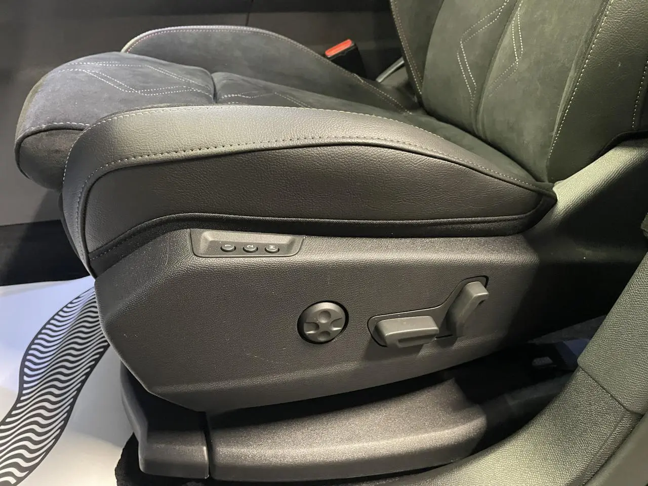 Gros plan sur le réglage électrique du siège avant gauche en Alcantara noir du DS7 Crossback noir métallisé.