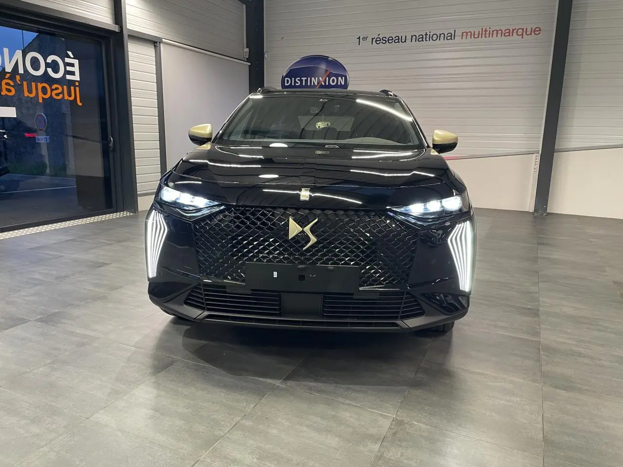 Vue frontale d'un DS7 Crossback noir métallisé avec calandre DS Wings et feux LED verticaux allumés.