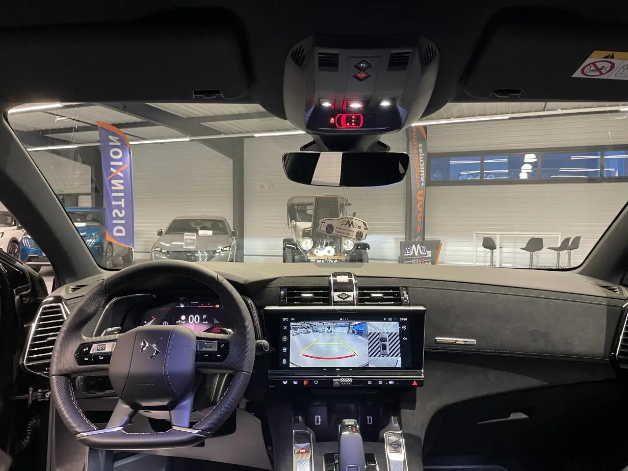 Vue intérieure avant du DS7 Crossback noir métallisé, tableau de bord et écran tactile affichant la caméra de recul.
