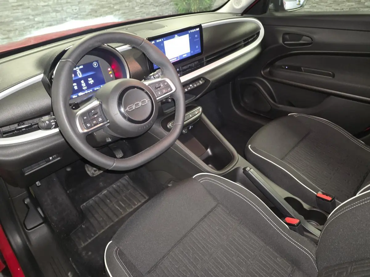 Vue intérieure avant droite du Fiat 600 1.2 Hybrid 2024 avec tableau de bord noir mat et volant Soft-Touch.