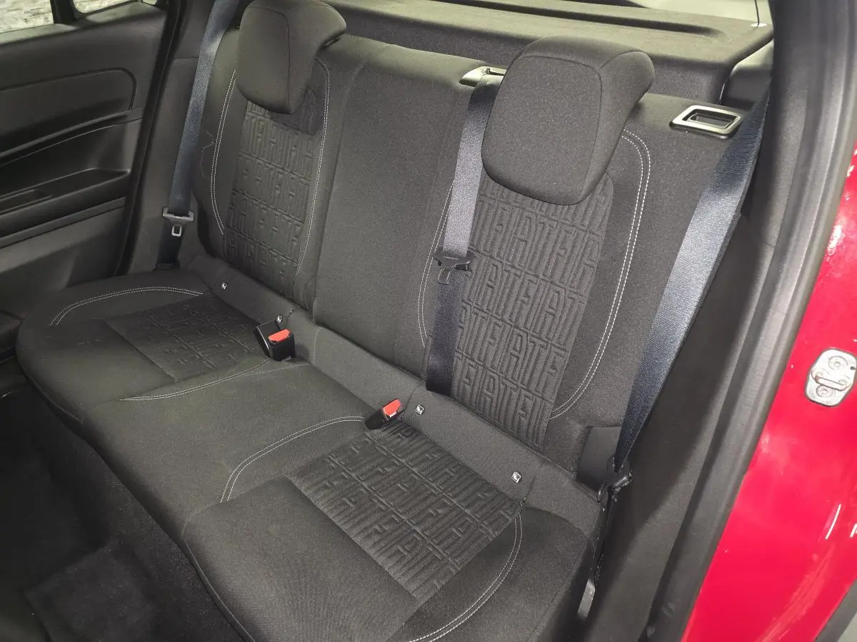 Vue intérieure arrière droite de la banquette noire avec motifs FIAT, ceinture et portière rouge visible du FIAT 600 2024.