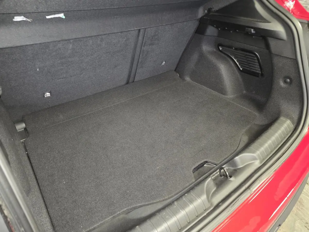 Coffre ouvert vu de l'arrière droit d'une FIAT 600 1.2 Hybrid rouge, avec tapis de sol noir et garnitures intérieures.