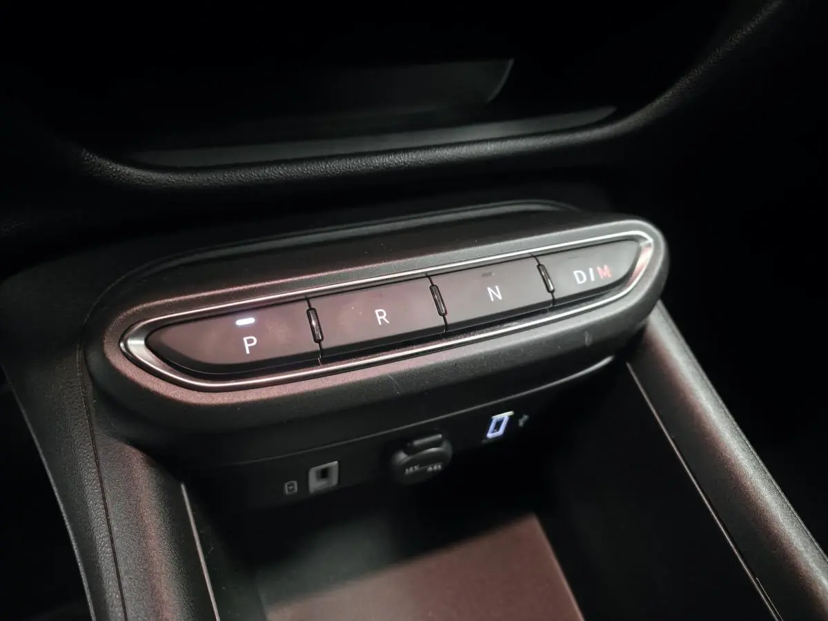 Gros plan sur la console centrale noire de la Fiat 600 Hybrid 2024 avec boutons de sélection de boîte auto éclairés.