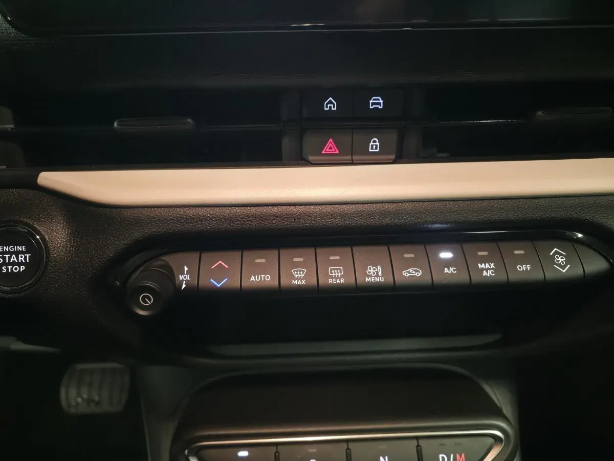 Vue rapprochée de la console centrale noire et beige du Fiat 600 rouge 2024, avec commandes climatisation et bouton start/stop.