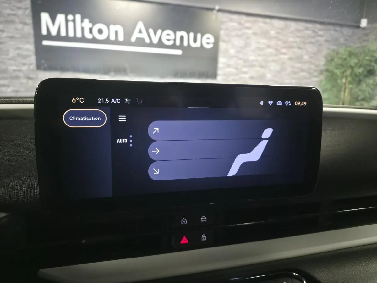 Écran tactile central de la FIAT 600 rouge 2024 affichant le réglage de la climatisation, vue intérieure frontale.