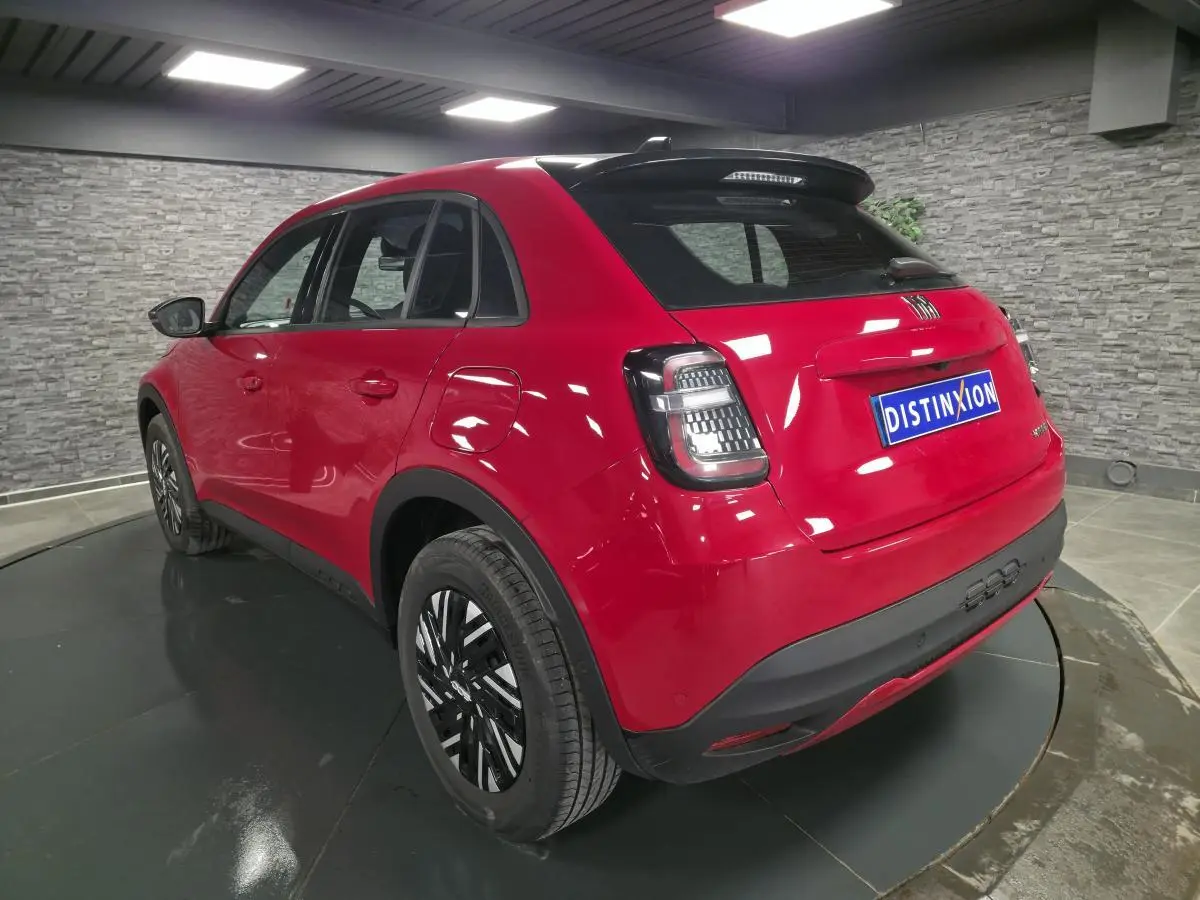 Vue 3/4 arrière droite d'une FIAT 600 rouge 2024 avec jantes bicolores et toit noir brillant.