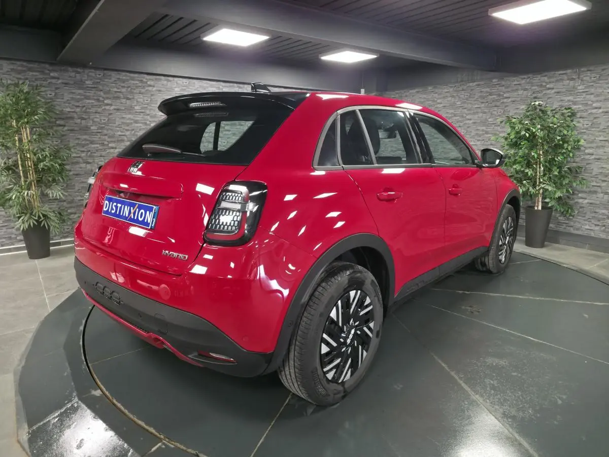 Vue 3/4 arrière droite d'une FIAT 600 rouge 2024 avec toit noir, feux arrière LED et jantes acier bicolores.