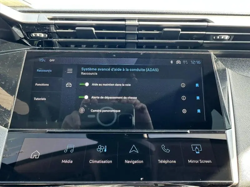 Vue rapprochée de l’écran tactile central de la Peugeot 308 2025 affichant les aides à la conduite, avec tableau de bord noir.