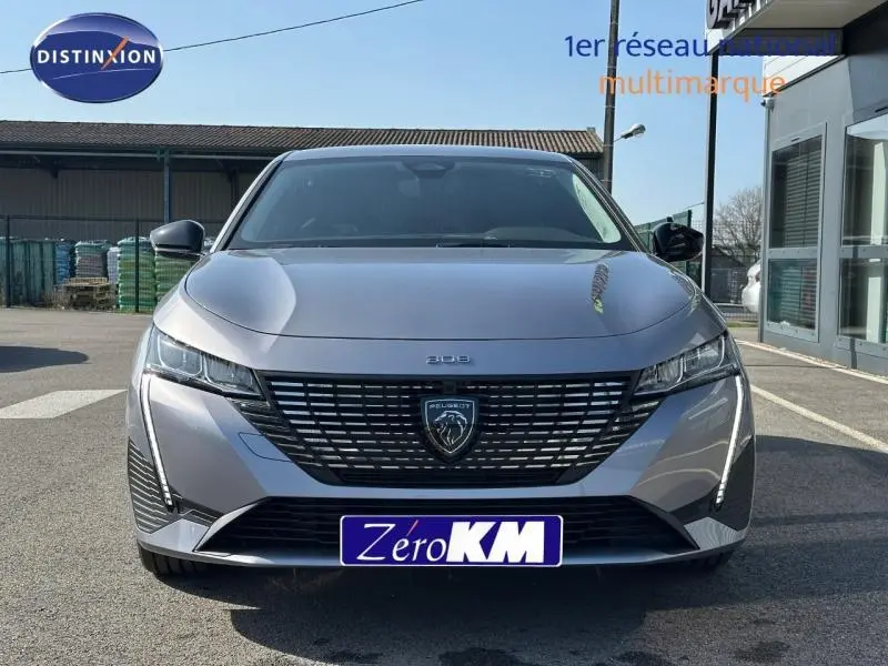 Vue avant frontale d'une Peugeot 308 gris Artense avec calandre noire et feux LED verticaux allumés.
