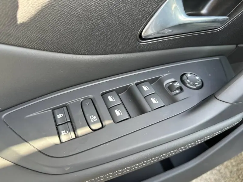 Vue rapprochée du panneau de commandes des vitres et rétroviseurs côté gauche en plastique gris sur Peugeot 308 2025.