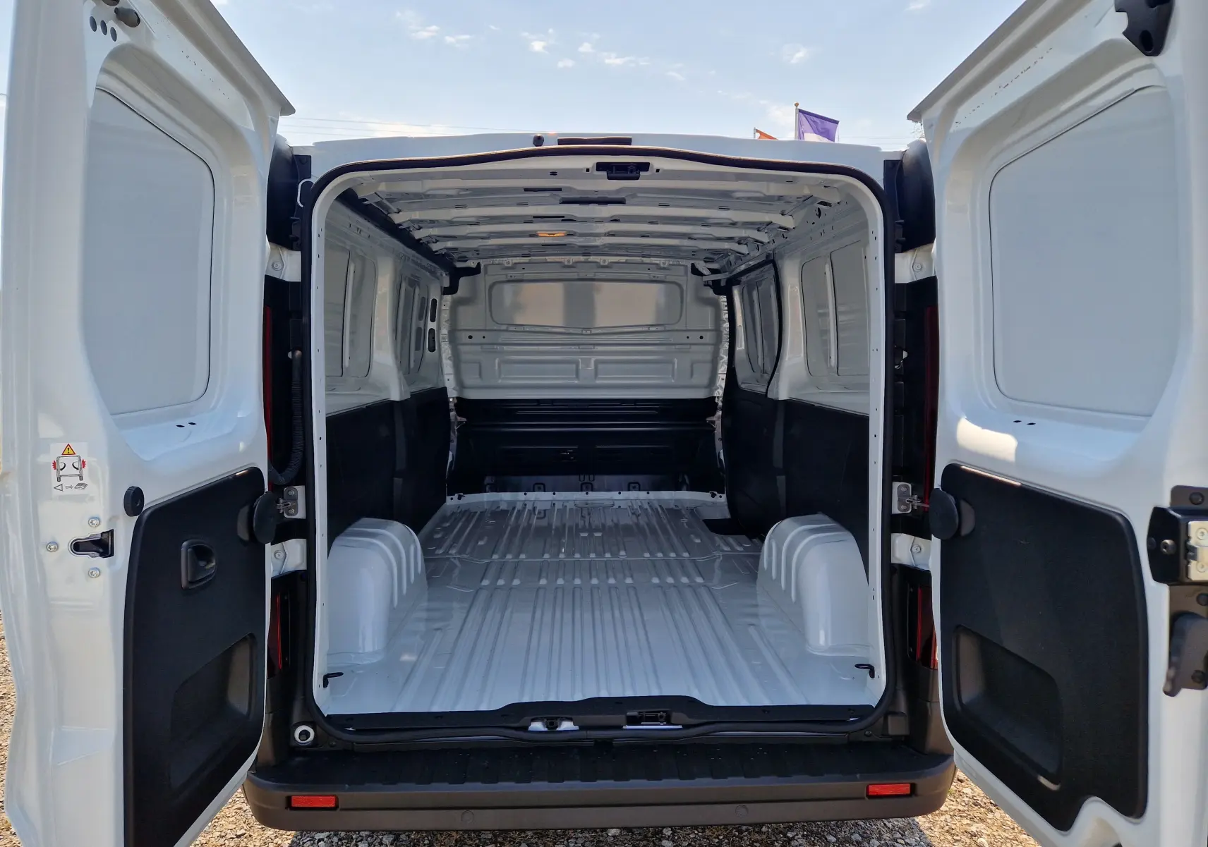 Vue arrière ouverte du Renault Trafic Fourgon blanc L2H1, montrant l’espace de chargement vide et les portes battantes.