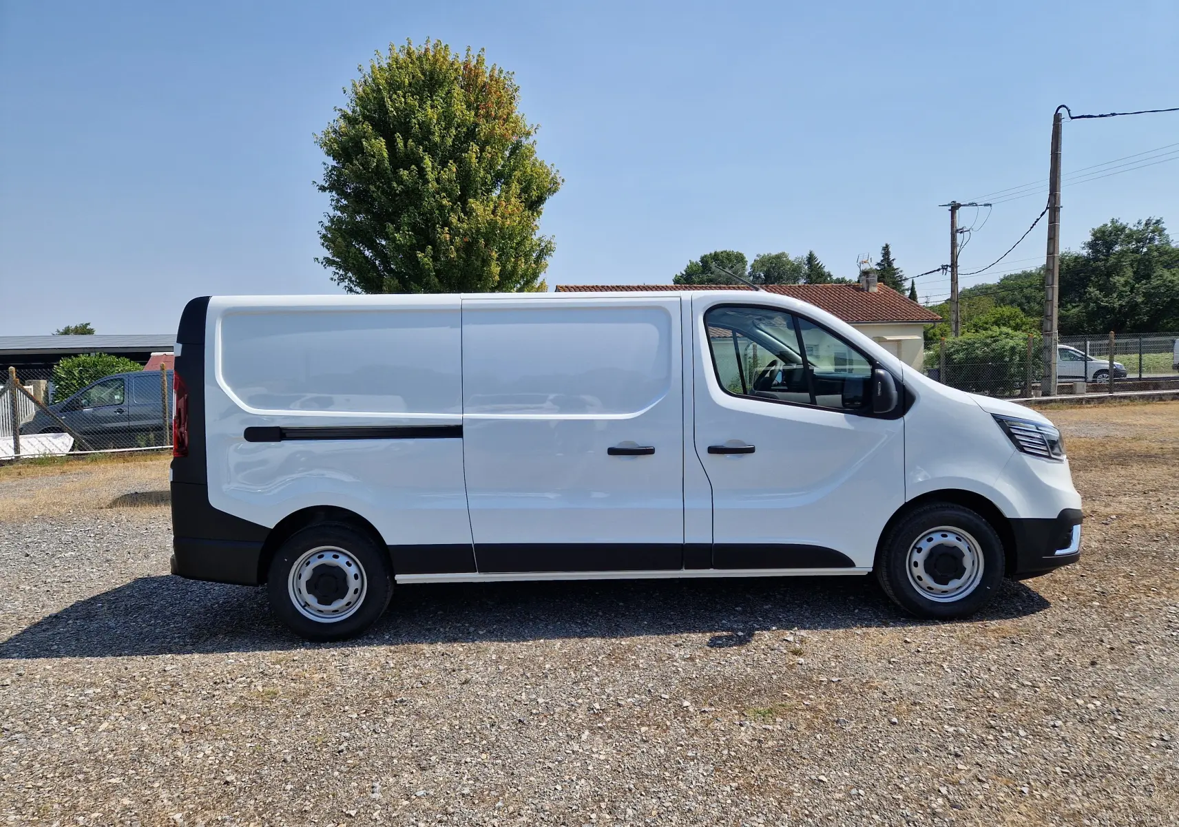 Renault Trafic Fourgon blanc vu de profil côté droit, avec porte latérale coulissante et jantes acier noires.