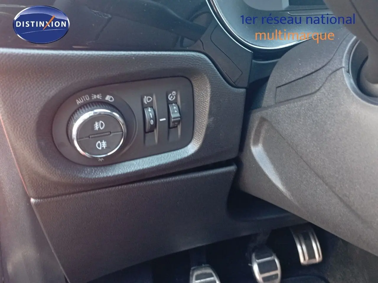 Détail du panneau de commandes d'éclairage et des pédales côté conducteur de l'Opel Corsa rouge 2023 avec toit noir.