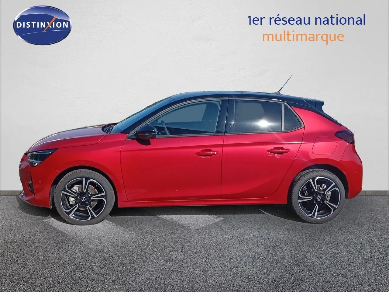 Profil côté gauche d'une Opel Corsa 2023 rouge Kardio métal avec toit noir et jantes alliage noires.