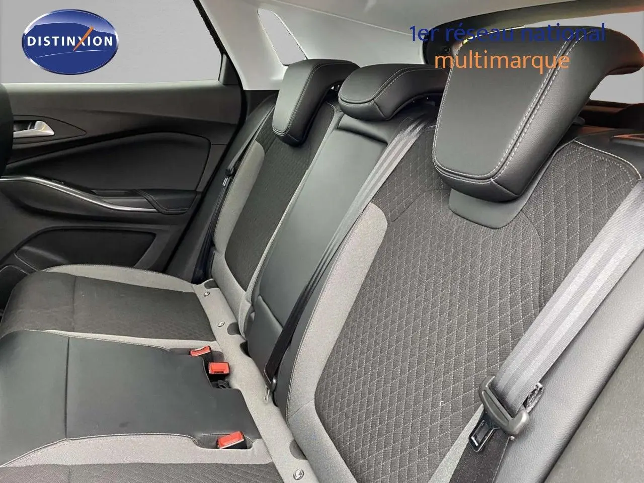 Vue intérieure du siège arrière droit de l’Opel Grandland X 2021, tissu gris et cuir noir avec ceintures de sécurité visibles.