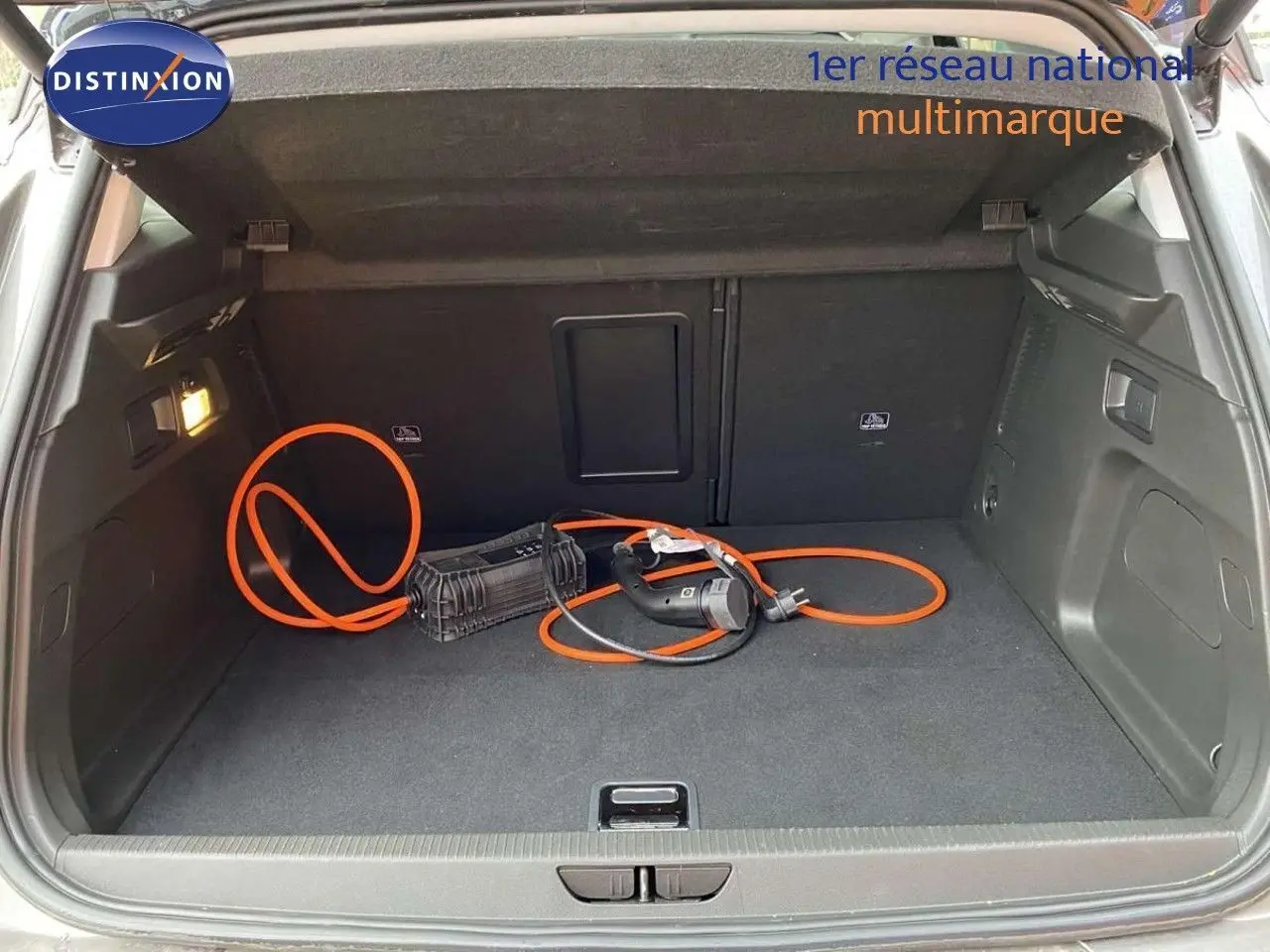 Coffre ouvert d’un Opel Grandland X 1.6 Hybrid Turbo 2021, vue arrière, avec câble de recharge orange visible.