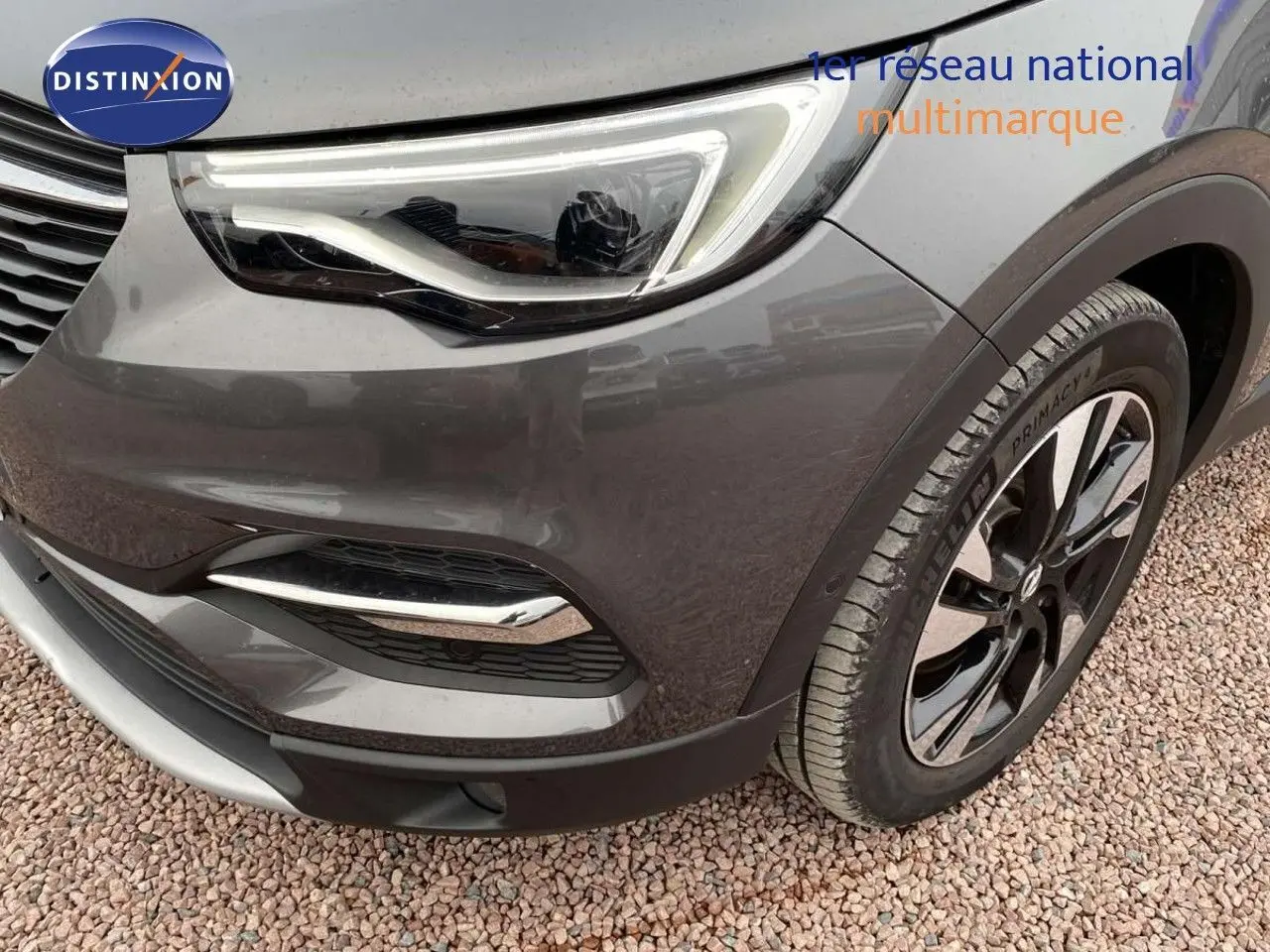 Gros plan sur l'avant droit de l'Opel Grandland X gris Pierre de Lune, mettant en valeur le phare LED et la roue alliage.