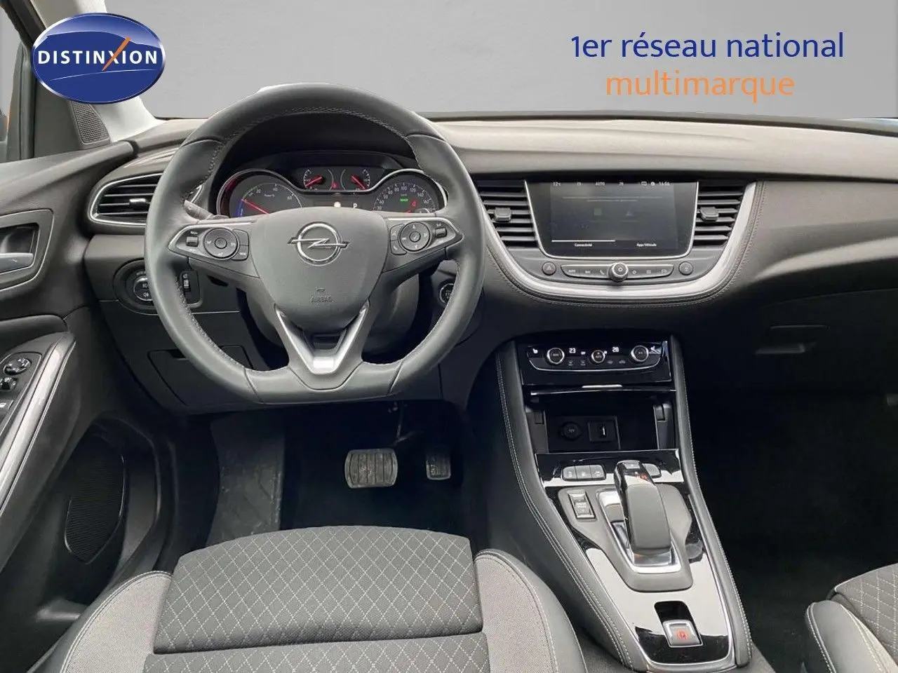 Vue intérieure centrée sur le volant et la console centrale d’un Opel Grandland X 1.6 Hybrid Turbo 2021 en finition noire.
