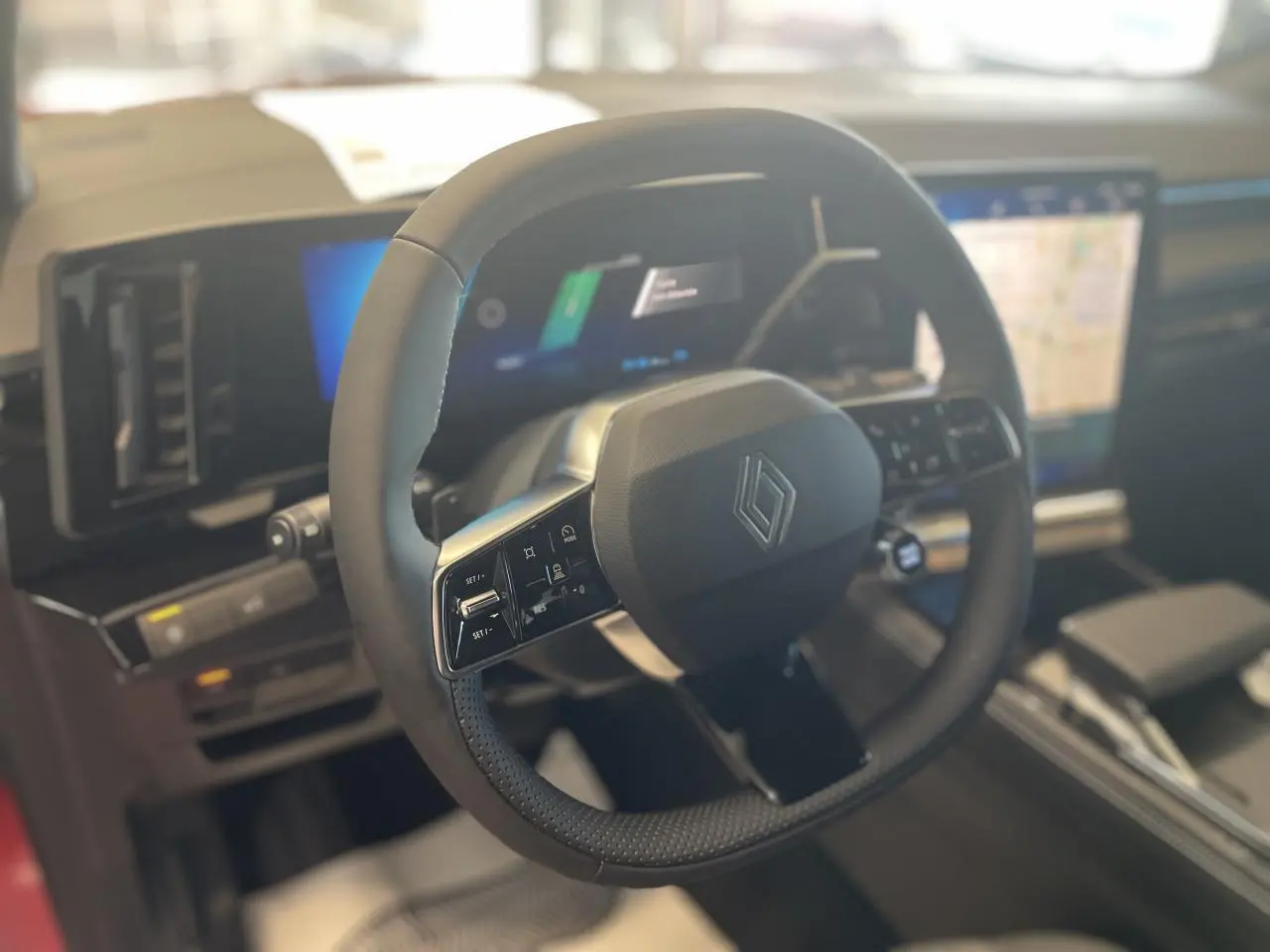 Vue intérieure centrée sur le volant noir de la Renault Rafale 2025 avec tableau de bord numérique et écran tactile.