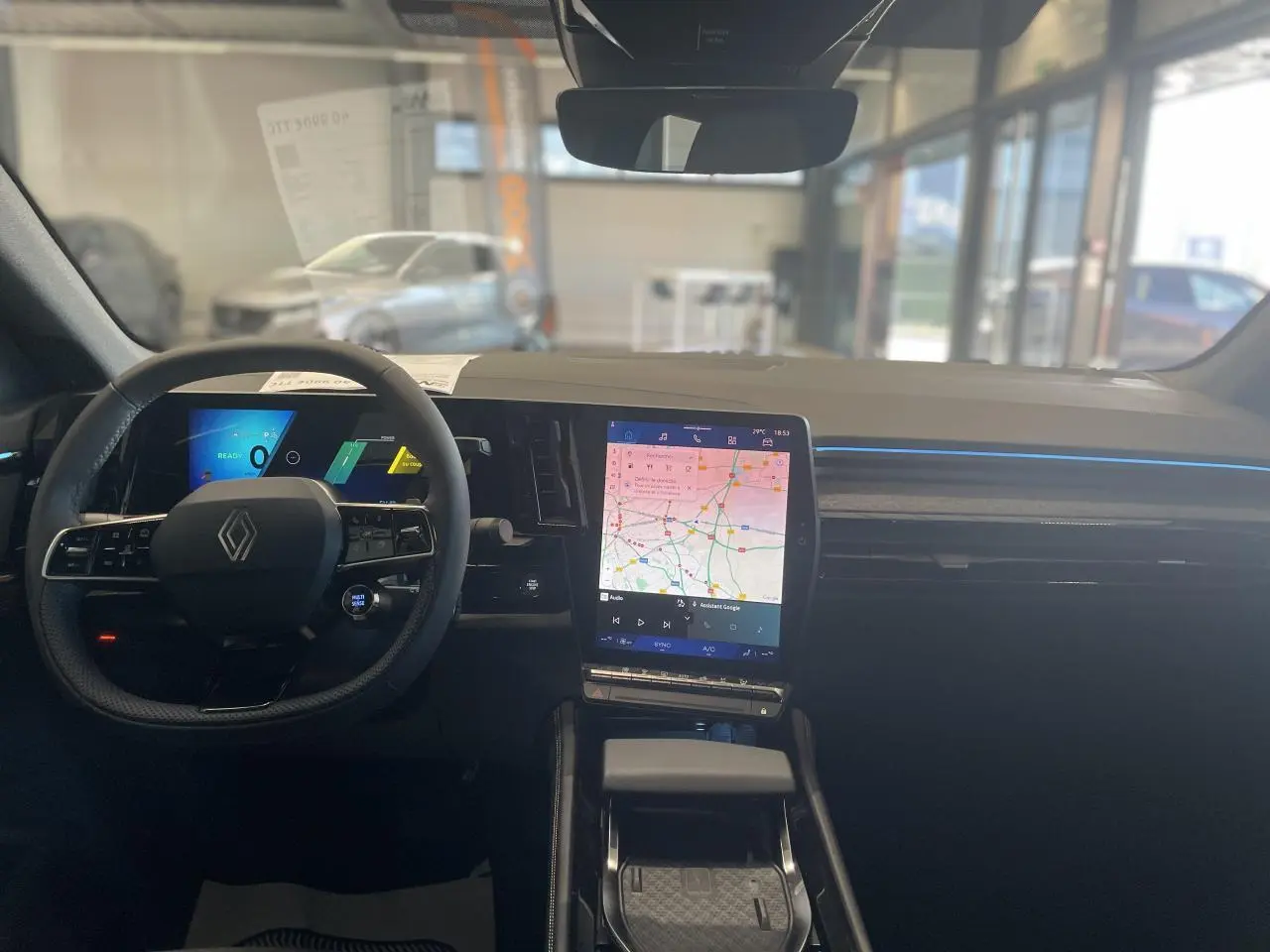 Intérieur de la Renault Rafale 2025 vu de face, tableau de bord noir avec écran tactile vertical affichant une carte.