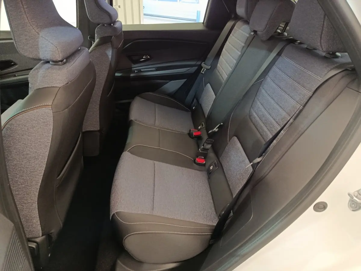 Vue intérieure côté droit sur la banquette arrière grise et noire du Renault R5 Techno 150 ch 2025, porte blanche ouverte.