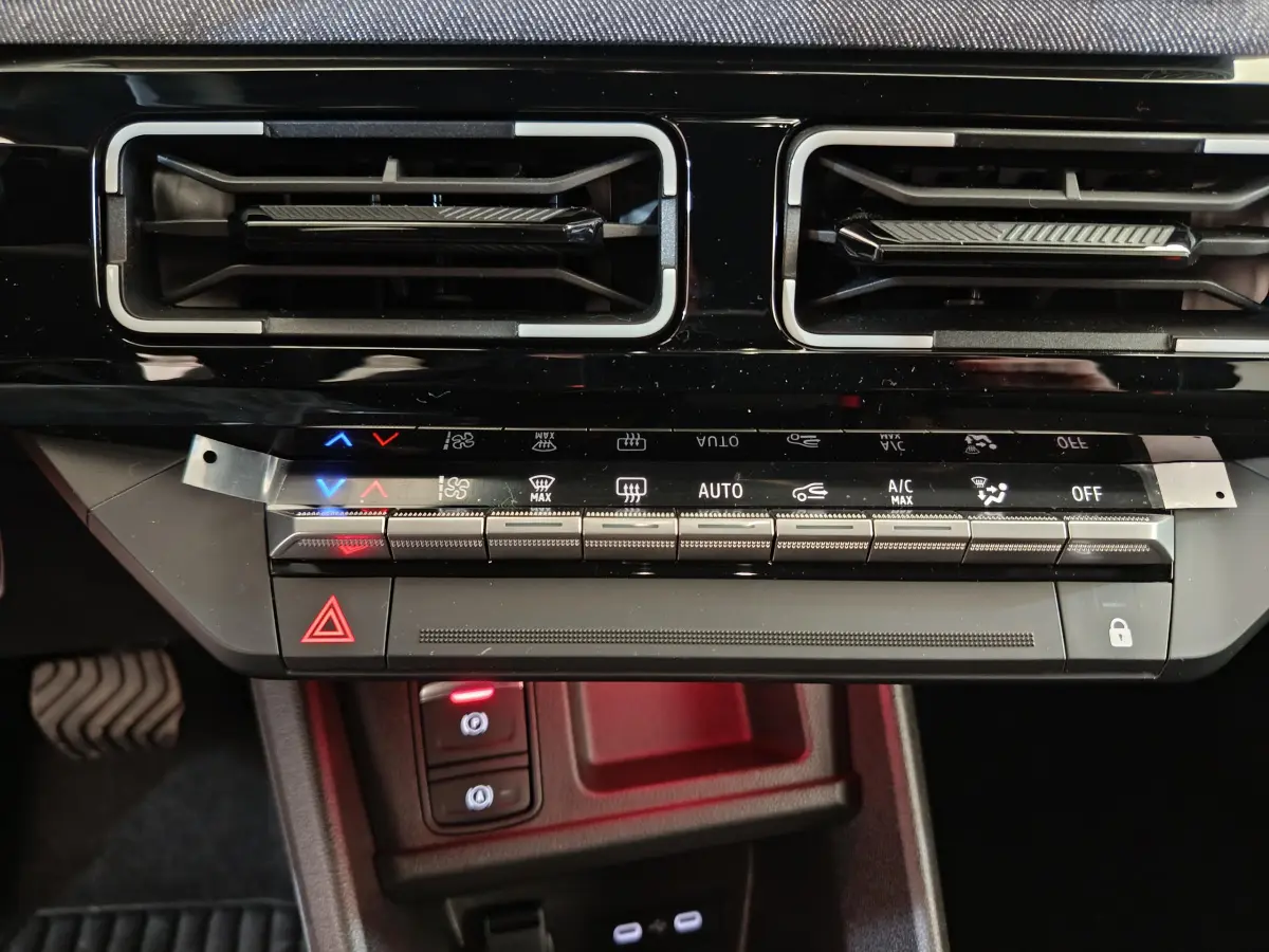 Détail du tableau de bord noir de la Renault R5 Techno 150 ch, avec commandes climatisation et boutons lumineux.