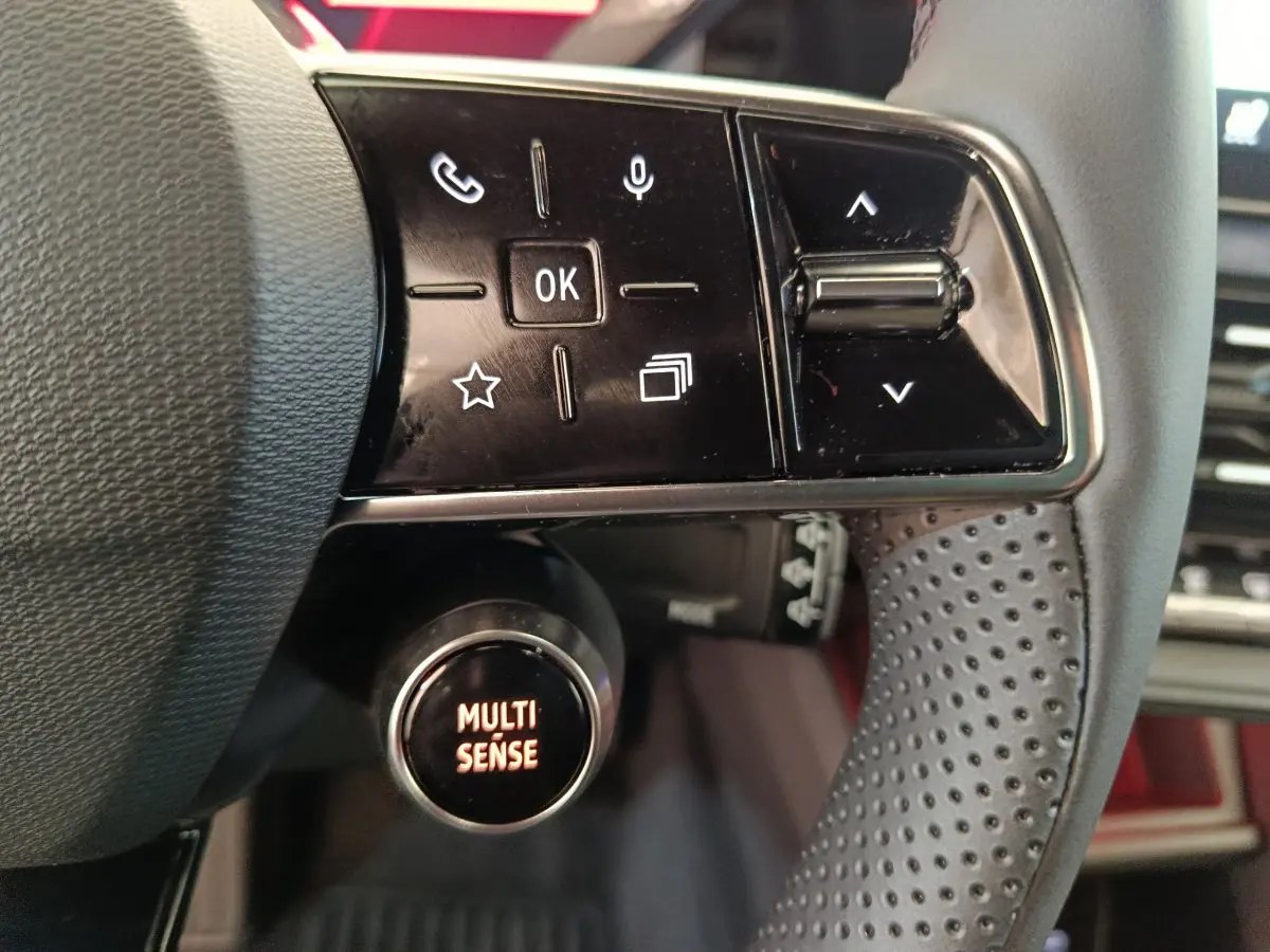 Gros plan sur le volant noir perforé de la Renault R5 Techno 150 ch, avec commandes multifonctions et bouton Multi Sense.