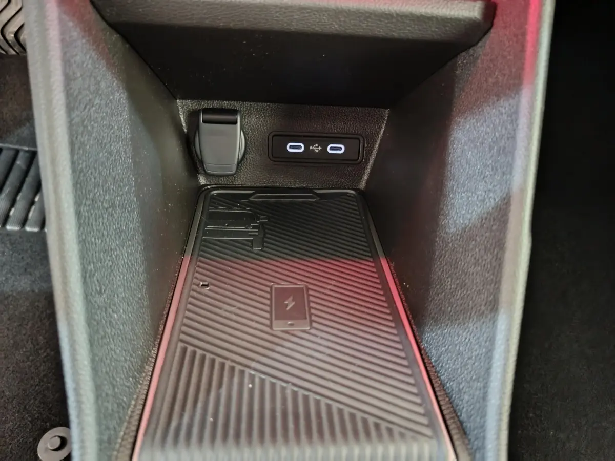 Gros plan intérieur sur la zone de recharge par induction noire avec prises USB et prise 12V dans une Renault R5 blanche 2025.