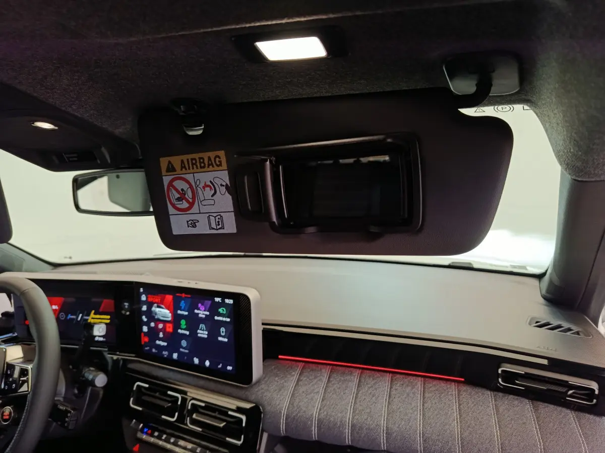 Intérieur avant droit de la Renault R5 Techno 2025, tableau de bord clair avec écran tactile et éclairage d’ambiance rouge.