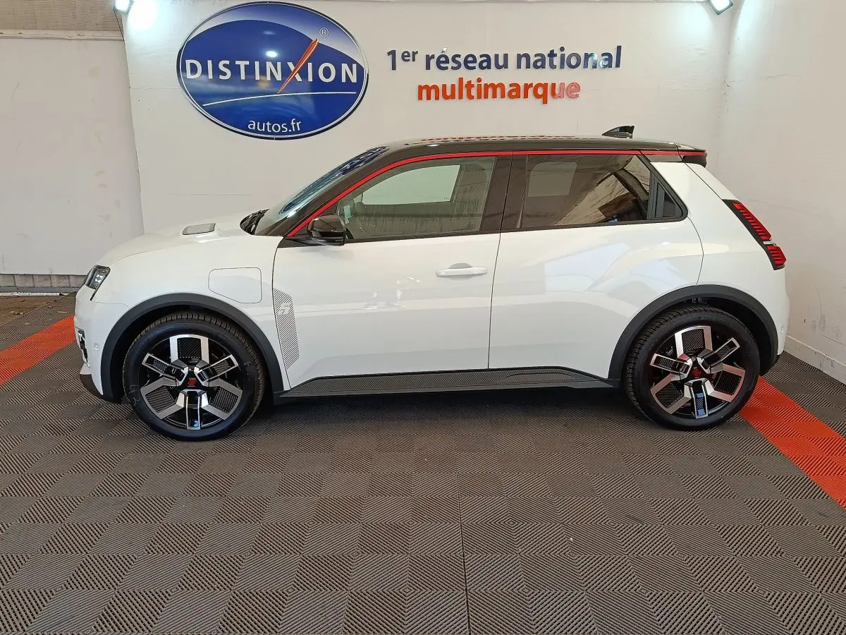 Profil droit d'une Renault R5 Techno 150 ch blanche avec jantes noires et toit noir souligné de rouge.