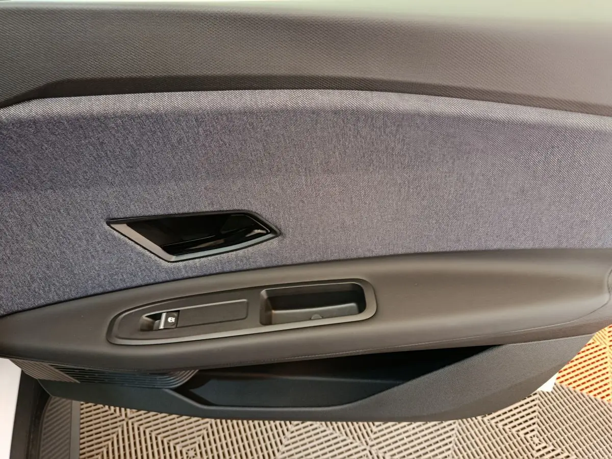 Gros plan sur la garniture intérieure de porte côté conducteur de la Renault R5 Techno blanche, tissu gris et plastique noir.