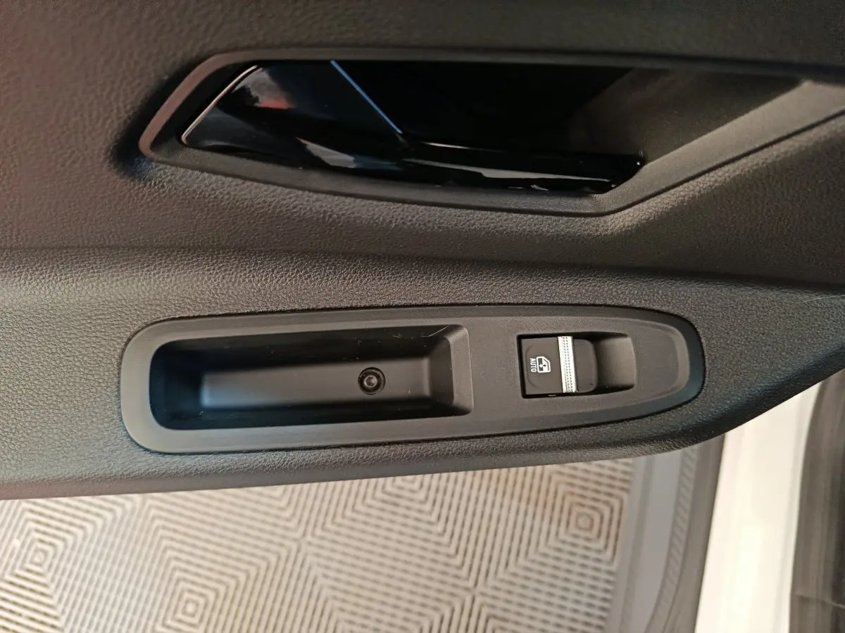 Gros plan sur la commande de lève-vitre côté conducteur d’une Renault R5 Techno blanche, intérieur noir.