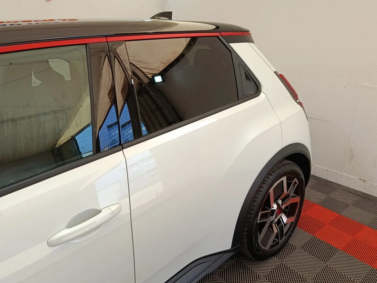 Vue latérale droite arrière d'une Renault R5 Techno blanche avec toit noir et jantes stylisées multicolores.